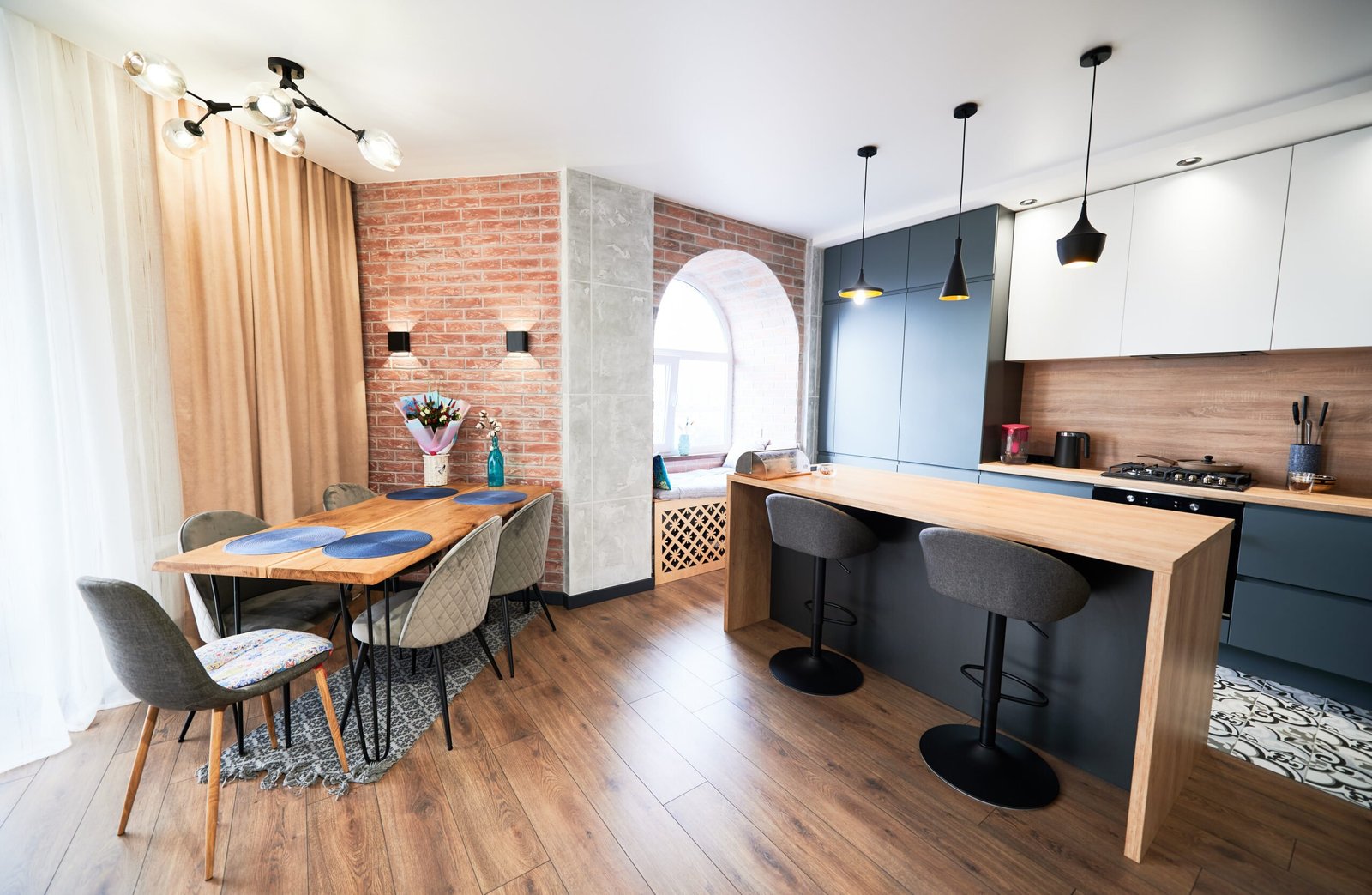 Living room and kitchen studio in dark blue color with modern furniture table, chair and stylish lamps. Concept of stylish modern interior kitchen with bar table.